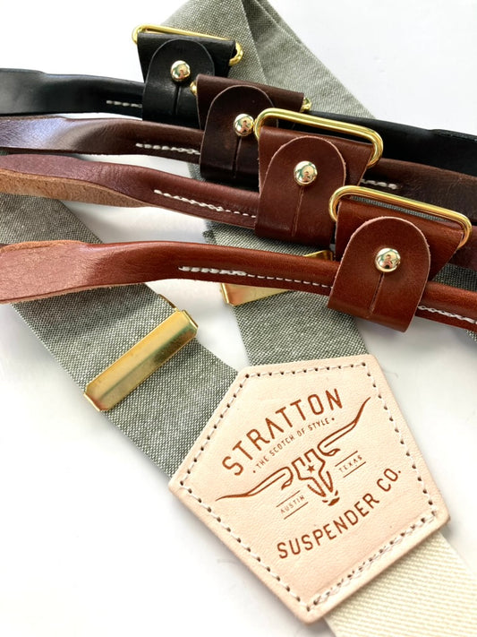 Sage green linen wedding suspenders with ivory elastic back strap, gold adjusters, and four leather button-on options in black, chocolate, cognac, and tan.